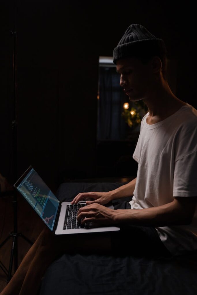 Side View of a Man in a Beanie Using a Laptop